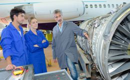 A mechanic teaching two others about a plane engine A mechanic teaching two others about a plane engine