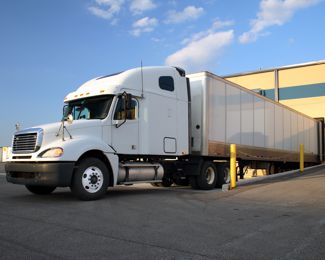 Clean white semi with trailer at a loading dock