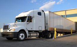 Clean white semi-truck and trailer at loading dock Clean white semi-truck and trailer at loading dock
