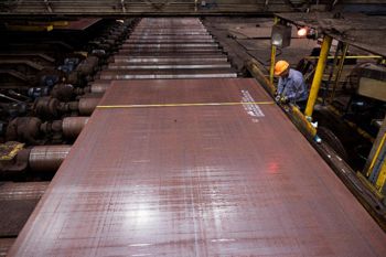 Man with a yellow hard hat working on a sheet of steel